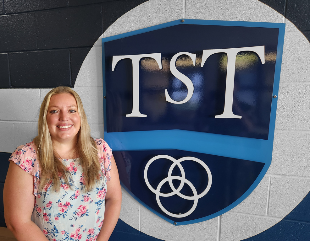 Brittany Kelly standing by TST logo