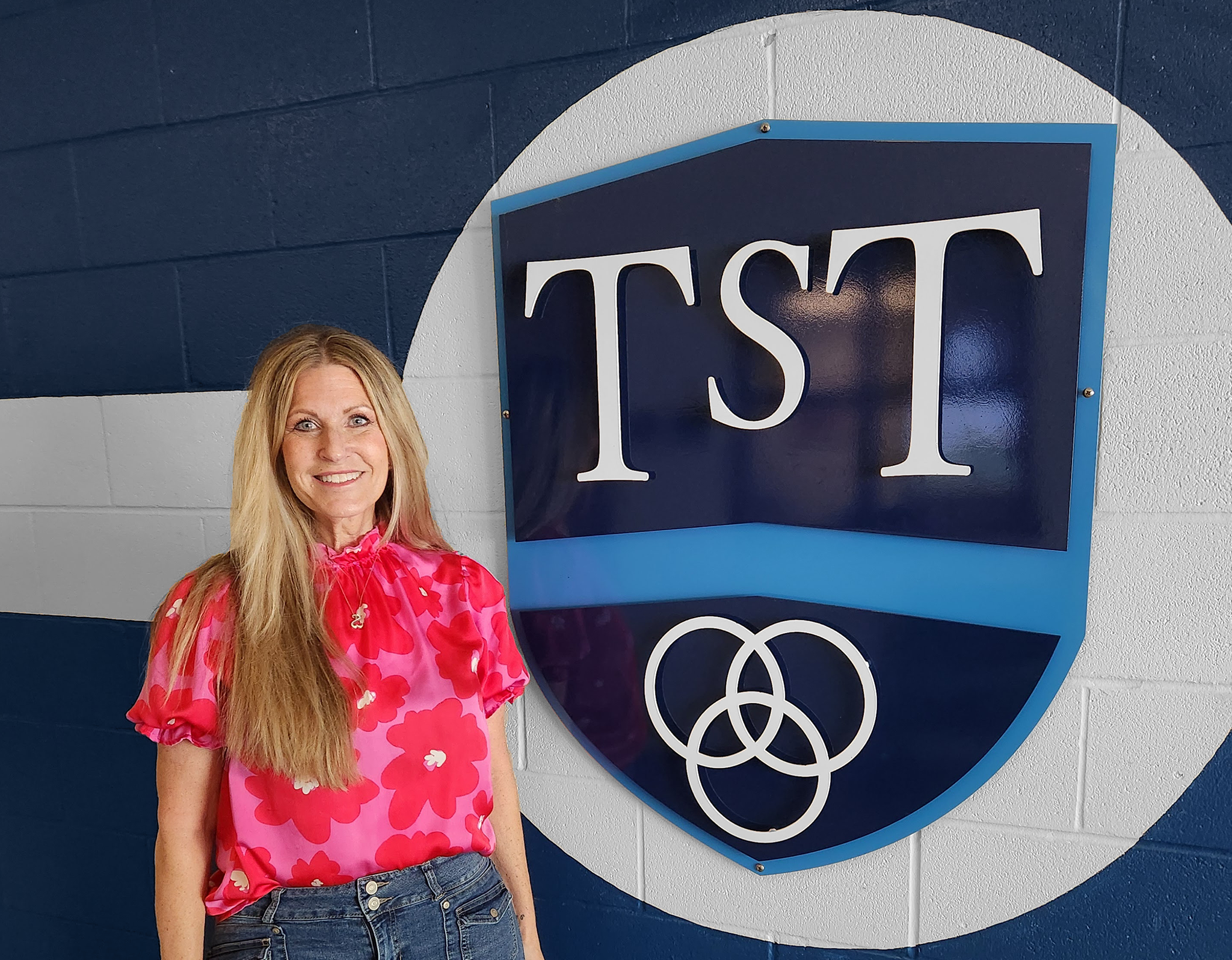 Diane Shelton standing by TST logo